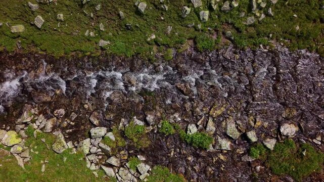Aerial view of rushing water flowing over rocky stream bed