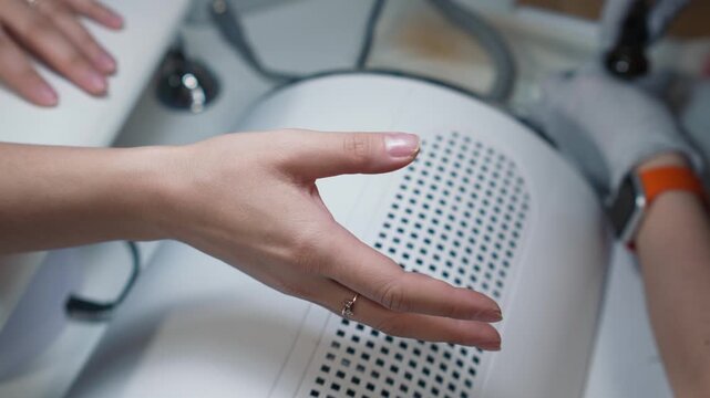 Applying primer to natural nail plate by manicure technician in beauty salon as an essential nail preparation step