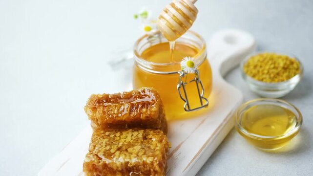 Fresh honey in jar with honeycomb and bee pollen on white board