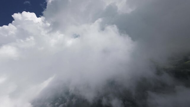 Aerial view descending through clouds to mountainous terrain
