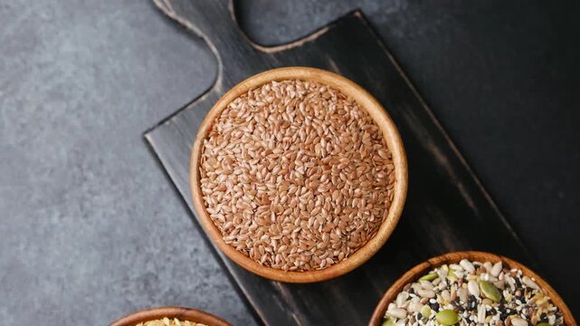 Two bowls of seeds on a dark cutting board with a textured background