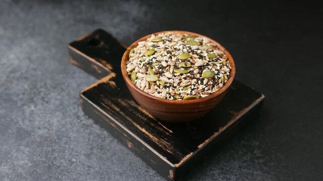 Mixed seeds in a wooden bowl on a dark textured background