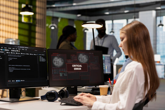 Female software developer in a technology startup office struggles to fix application errors and computer glitches while writing code.