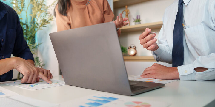 Business team analyzing artificial intelligence data and financial charts on laptop in modern office meeting