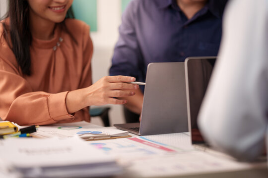 Cropped Asian businesswoman pointing at laptop screen showing data during meeting