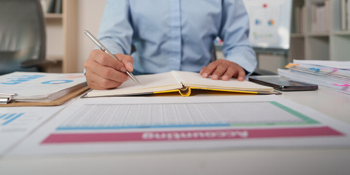 Business person writing in notebook for financial accounting and budget planning