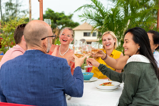 Diverse men and women toasting wine at an outdoor social dinner