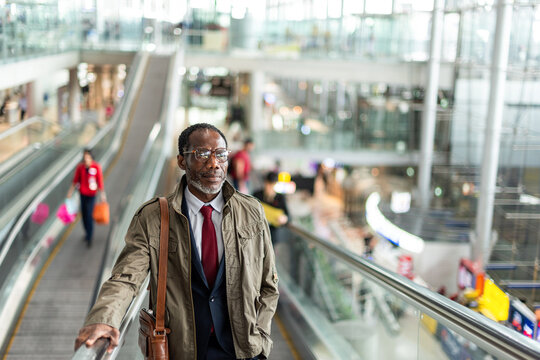 Businessman on airport escalator journey.