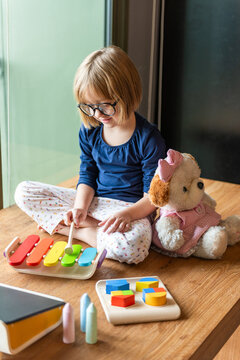 Child playing colorful xylophone indoors.