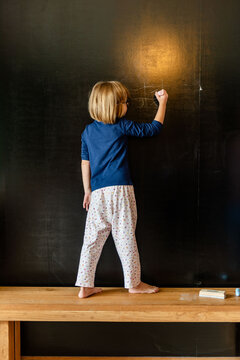 Child drawing on chalkboard creatively.