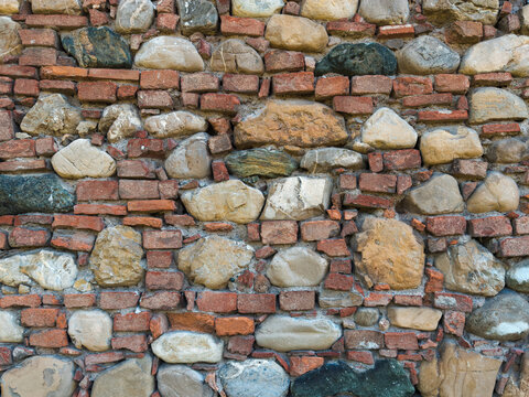 Ancient stone wall texture with old red bricks and cobblestones mix.