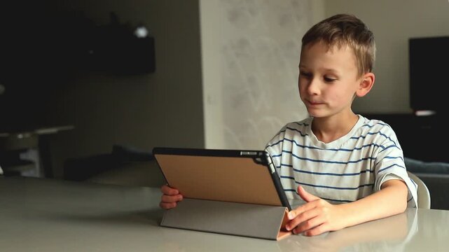 Young boy sits with a tablet at home while completing speech therapy and educational exercises, combining digital learning with language development practice.
