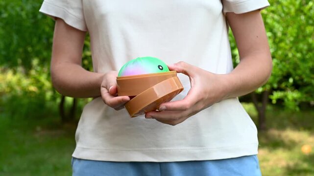 Girl playing colorful dumpling shaped squishy toys outdoors in a green garden. Sensory toy, fidget activity, relaxation and playful lifestyle concept.