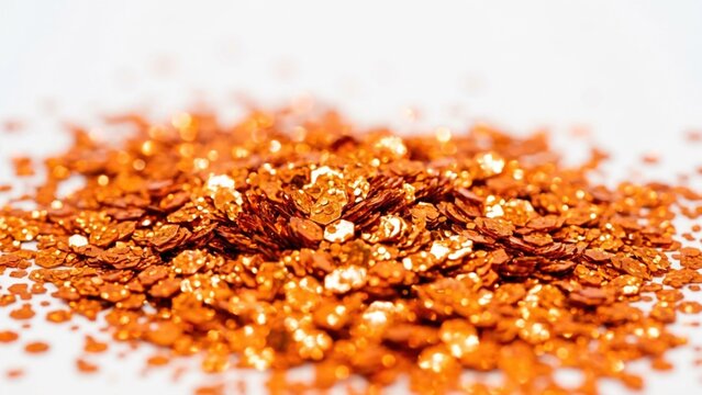Abstract pile of shiny orange glitter particles on white background