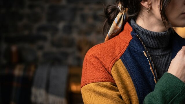 Stylish woman wearing a colorful wool patchwork jacket in a cozy rustic interior