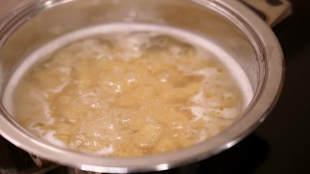 Pasta boiling in bubbling water inside stainless steel pot.
