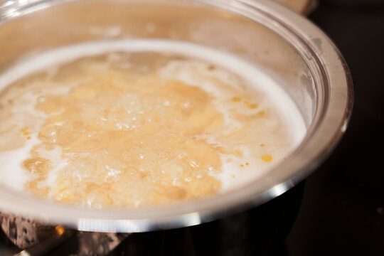 Pasta boiling in bubbling water on stove in stainless steel pot. 