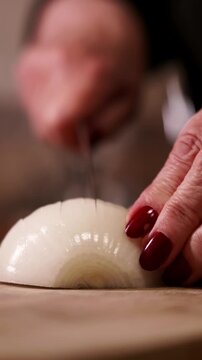 Slicing onion with knife close up of woman's hands.