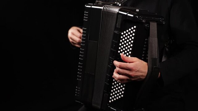 Close-up video of an accordion player performing, focusing on hands, keys, buttons, and moving bellows against a black background, capturing rhythm, movement, and musical detail.