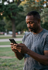 Fototapeta premium Digital inclusion and senior tech, mature man using a smartphone in a park for mobile communication and social connection in a natural outdoor setting