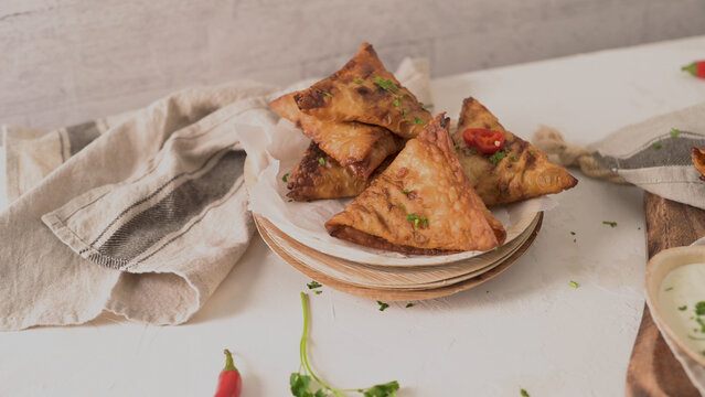 Crispy fried samosas on a plate with herbs