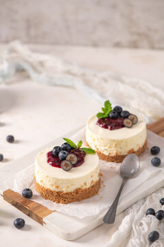 Two mini cheesecakes with blueberry topping on a wooden board
