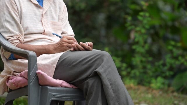 Person Writing Notes in Notebook While Sitting Outdoors