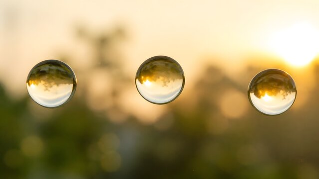 Three crystal glass balls reflecting a golden sunset in nature with beautiful bokeh