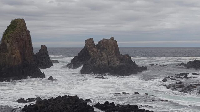 岩に波が打ち寄せる荒れた海の風景。