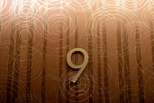 Golden number nine on textured circular pattern wallpaper