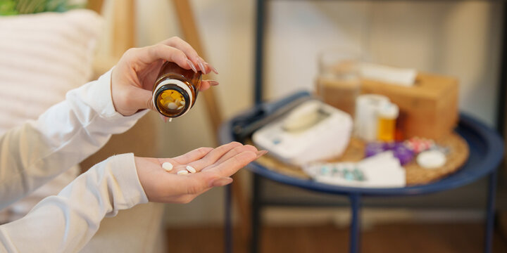 Cropped view of hands pouring pills from bottle for medical care at home