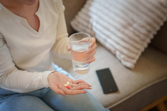 Cropped hands holding pills and glass of water for daily medication context