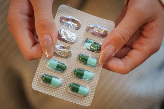 Cropped hands holding silver blister pack of medical capsule pills