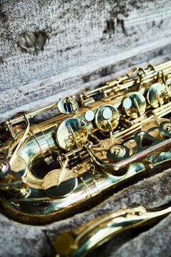 Vertical image of golden saxophone lying in open velvet case, representing street musicians gear. Close up shot suitable for music school promotion or jazz festival marketing