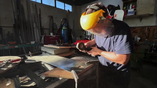 Skilled male worker using an angle grinder to cut a metal sheet. Sparks flying during the precision cutting process in a craftsman's workshop