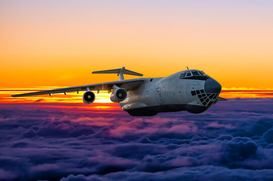 White wide body transport freight aircraft flies above the cumulus sunrise sky