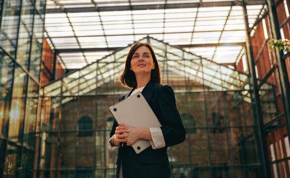 Businesswoman with a laptop under a glass atrium roof