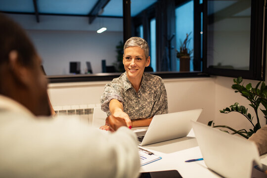 Smiling manager shaking hands with colleague in modern office