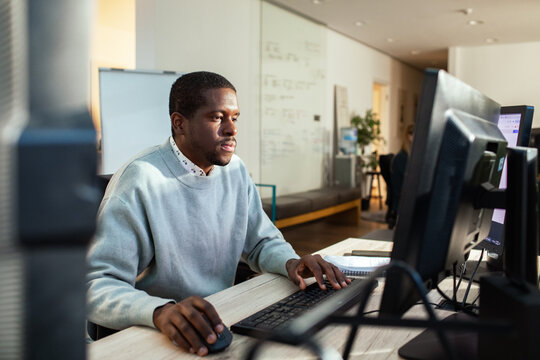 Young professional man working at desktop computer in modern office