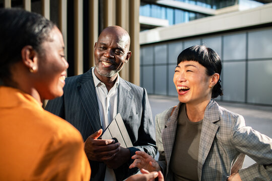 Diverse business colleagues laughing outside office building