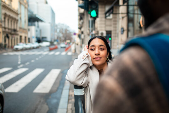 Young woman leaning on pole at city crosswalk