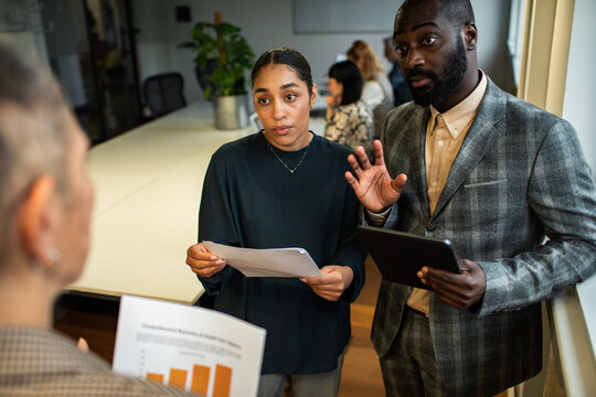 Coworkers reviewing report and data in conference room