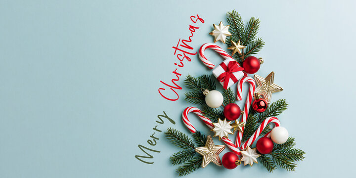Merry Christmas xmas celebration greeting card with text - Christmas ornaments in the shape of a christmas tree, isolated on bright blue background, top view flat lay