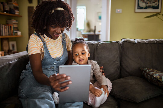 Mother and toddler using tablet on couch at home