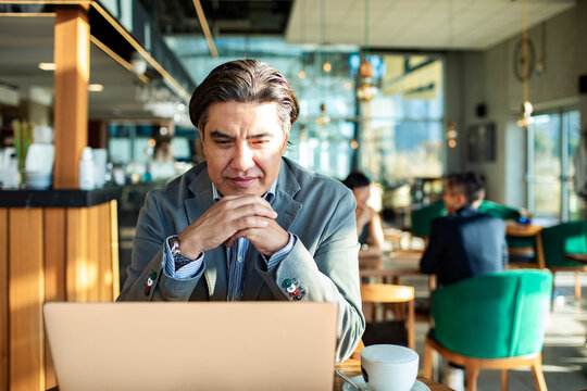 Business professional working on laptop in modern cafe