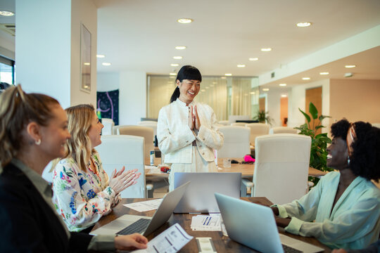 Diverse businesswomen applauding team leader in modern office meeting