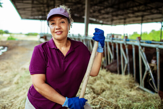 Confident female farmer with tool in cattle barn