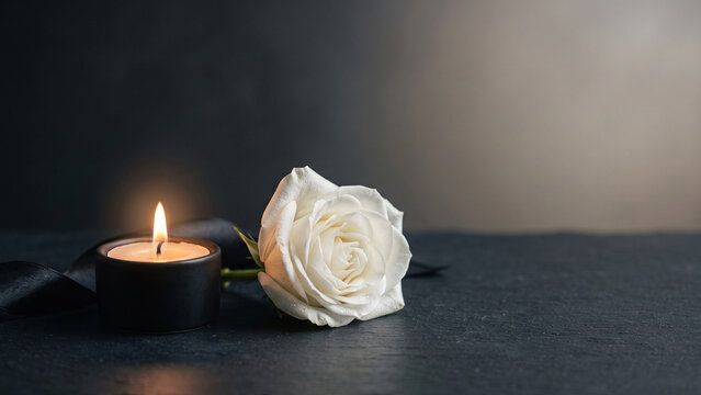 A warm memorial candle, white flower and black ribbon create a symbolic still life representing remembrance, compassion, hope and dignity during a National Day of Mourning