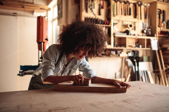 Woman sanding wood in a carpentry workshop