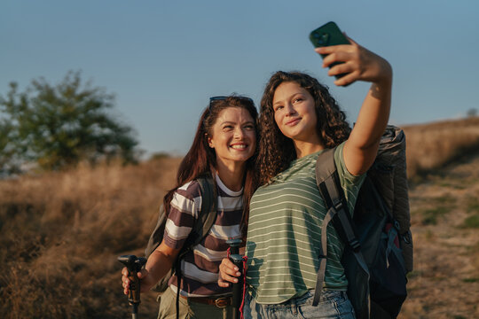 Two smiling women taking selfie during hiking adventure